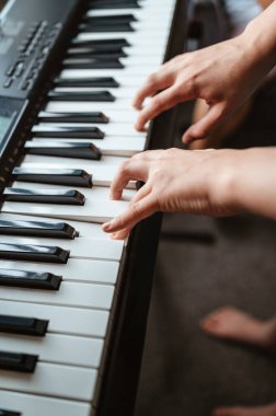 Evde sentezleyici çalan çocuğun elleri.