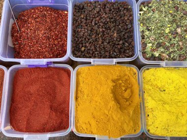 Markette konteynerlerde sergilenen canlı baharatlar ve kurutulmuş meyveler.
