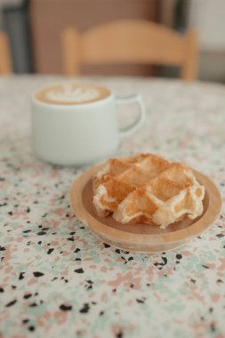 Belçika waffle 'ı ve latte, yumuşak arka planlı terrazzo masasında.