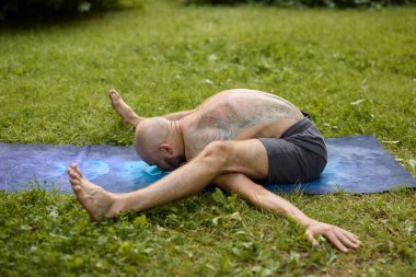 Yoga pratisyeni bahçede ileri esneklik gösteriyor.