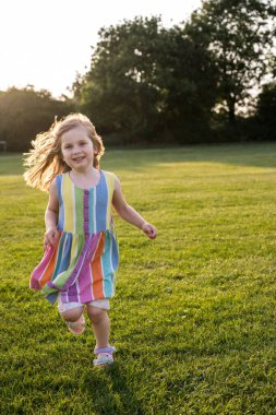 Gün batımında parkta koşan küçük kız.