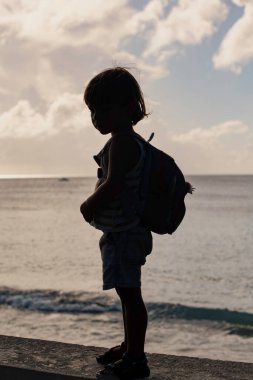 Okyanusun önündeki dramatik genç çocuk silueti