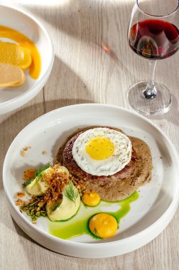 Biftek, kızarmış yumurta sosu ve bir bardak şarap.