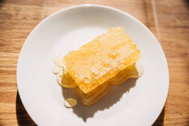 Tabağa çiğ bal damlayan taze bal peteği