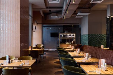 Masaları ve yeşil dekorları olan modern bir restoranın yemek salonu.