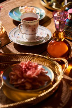 Süslü bir tabakta servis edilen çay, masada renkli eşyaların yanında.