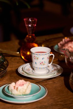 Narin bir fincanda servis edilen çay ve ahşap masada tatlı.
