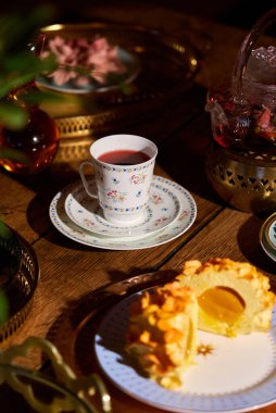 Sıcak bir ortamda çay ve tatlının tadını çıkarıyor.