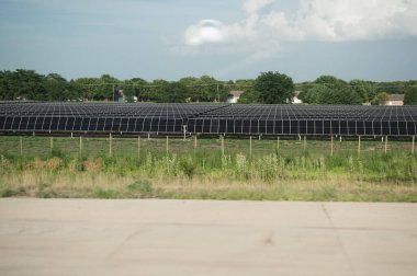 Banliyö evleri ve yeşil ağaçların yakınındaki büyük güneş paneli dizisi