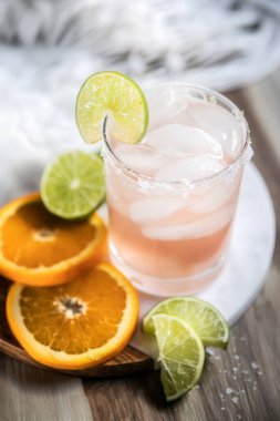 Limonlu ve portakallı margarita kokteyli ahşap yüzeyde tazeleniyor.