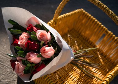 Dışarıda sarı sepetin içinde bir buket gül