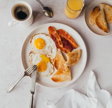 Bir tabak domuz pastırması, yumurta, kahvaltıda içeceklerle tost..