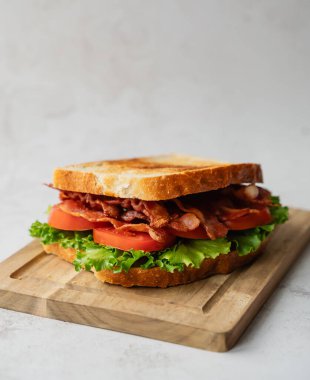 Tahta tahtadaki BLT sandviçi ve beyaz arkaplanı kapat.