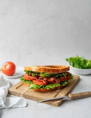 Tahta tahtadaki BLT sandviçi ve beyaz arkaplanı kapat.