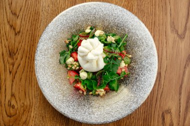 Sebze ve otlarla dolu bir tabakta burrata peyniri