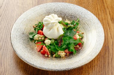 Sebze ve otlarla dolu bir tabakta burrata peyniri