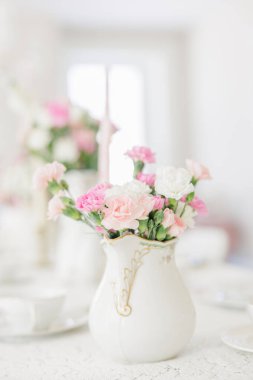 Zarif vazoyu dolduran pembe ve beyaz karanfiller.