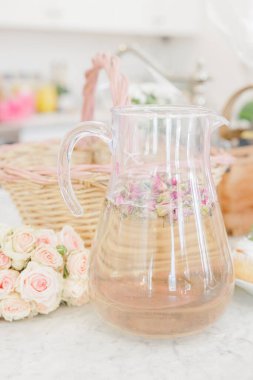 Gül yapraklı cam sürahi ve çiçek aranjmanı