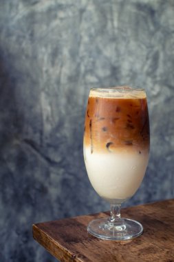 Buzlu latte, ahşap masada süt ve kahve arasında bölünmüş katman.