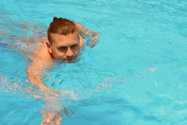 Genç adam havuzda yüzüyor.