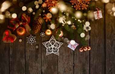 Noel ve yeni yıl kartı. Ağaç süslemeleri, kar taneleri, hediyeler ve tahta arka planda toplar.