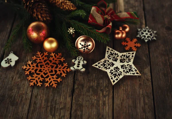 Noel ve yeni yıl kartı. Ağaç süslemeleri, kar taneleri, hediyeler ve tahta arka planda toplar.