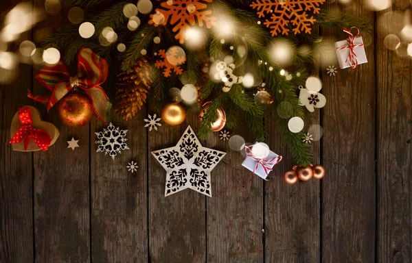 Noel ve yeni yıl kartı. Ağaç süslemeleri, kar taneleri, hediyeler ve tahta arka planda toplar.