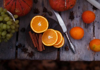Kesme tahtasındaki dilimlenmiş portakallar, balkabakları, mandalinalar, tarçın çubukları, üzümler ve yıldız anasonu sıcak şarap için eski masa / malzemeler