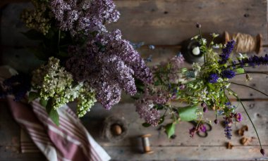 Eski bir masa üzerinde leylak demetleri ve kır çiçekleri. Eski moda bir hayat.