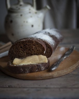 Tahta kesme tahtasının üzerinde taze pişmiş çavdar ekmeği çay ile çaydanlık. düz yat