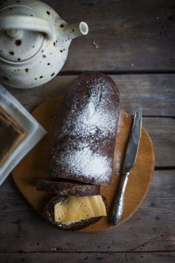 Tahta kesme tahtasının üzerinde taze pişmiş çavdar ekmeği çay ile çaydanlık. düz yat