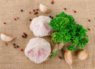 Sacks arka planında sarımsak, biber ve maydanoz.