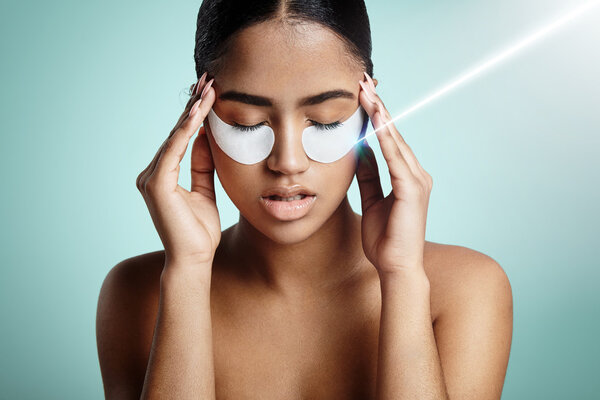 woman with eyes patches touching temples