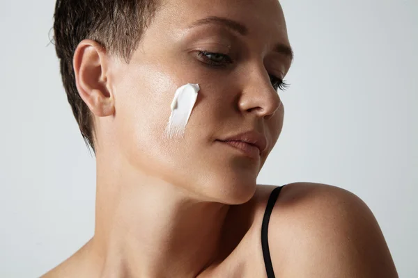 Femme avec crème sur la joue — Photo