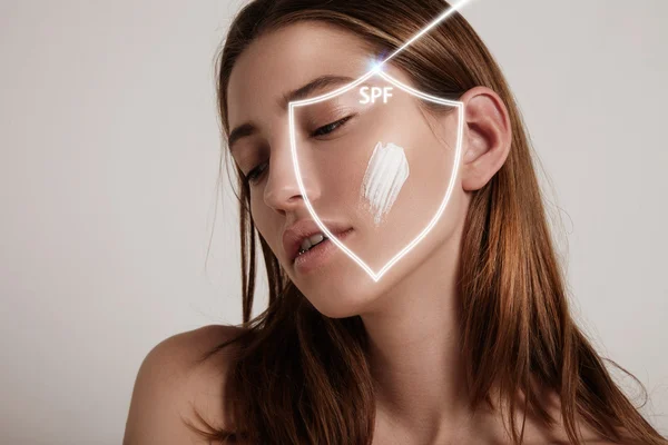 Mujer con crema en la mejilla —  Fotos de Stock