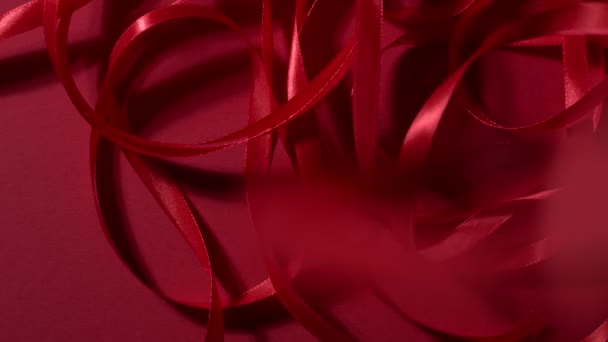 Many red silk shiny ribbons falling down on a matte ruby background. 4k quality top shot video footage. — 图库视频影像