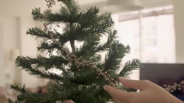 Ženské ruce zdobí zlatým věncem umělý vánoční stromeček. Closeup 4k vysoce kvalitní video záběry. — Stock video