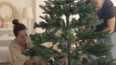 Ev kıyafetli bir çift yapay bir Noel ağacı yapıyor. Eğim yüksek kalite 4K video kaydı.