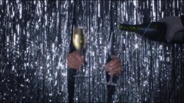 Işıl ışıl arka planda iki kadeh şampanya tutan eller. Bardağı dolduran bir el daha. Kadeh kaldırma ve kaybolma. 4K yüksek kalite video kaydı.