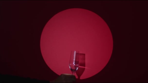 红色红宝石背景。一只手把杯子放在灯光下,侍者的手端着一杯闪闪发光的饮料.Confetti爆炸了高质量的录像镜头. — 图库视频影像