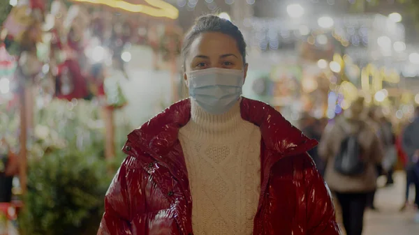 白种人年轻女士身穿红色宽松夹克，背带着圣诞节的医疗面具。中型肖像画. — 图库照片
