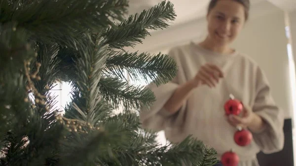 Giovane donna caucasica con i capelli castani che decorano un albero di Natale artificiale. Chiudi foto ad alta risoluzione jpg Immagine Stock