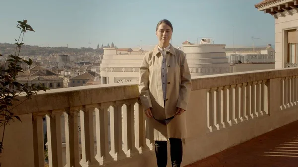 Donna caucasica è in piedi solitario sul balcone con una maschera facciale. Protezione dal coronavirus. Ritratto frontale medio full shot immagine ad alta risoluzione Foto Stock