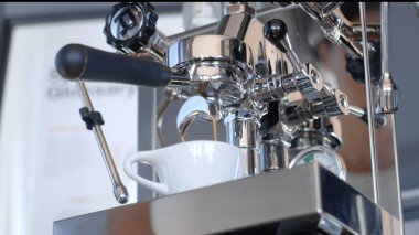 Beyaz bir seramik fincana çelik kahve makinesinden espresso çıkarmak. Düşük açı, yüksek kalite fotoğraf..