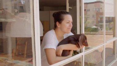 Genç siyah saçlı kadın gülümsüyor ve köpeğini pencereden dışarı çıkartıyor. Yine de yüksek kaliteli video..
