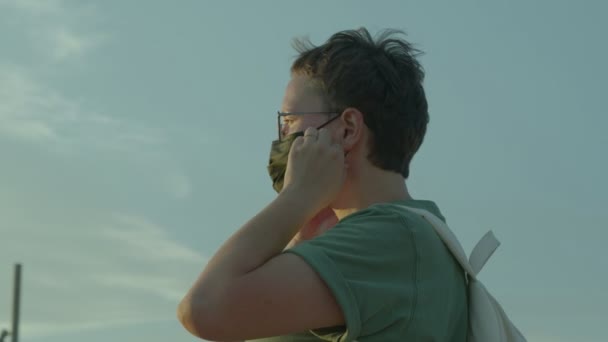 Tôt le matin ou le soir portrait vidéo de caucasienne jeune femme aux cheveux courts décoller masque de protection et respirations. — Video