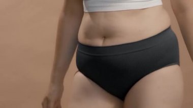 Karnı ve kalçalarına dokunan üzgün, iri yarı bir kadın. Yüksek kaliteli stüdyo videosu.