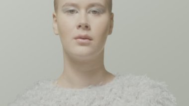 Beyaz elbise stüdyosundaki cesur beyaz kız mankeni, açık video portresi için poz veriyor.