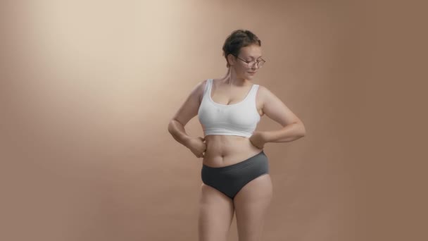 Plein corps figuré femme caucasienne positive en sous-vêtements apprécier et être fier de ses formes. Beige studio fond vidéo de haute qualité. — Video