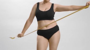 Siyah iç çamaşırlı beyaz kadın vücut pozitifliği için duygu sömürüsü yapıyor. Beyaz stüdyo arka planı yüksek kaliteli video.